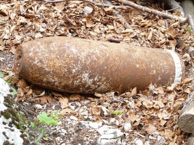 Old rusted explosive round buried in dirt